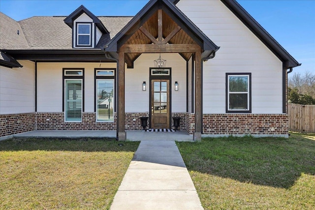 bungalow-style home with a porch, brick siding, a shingled roof, and a front lawn