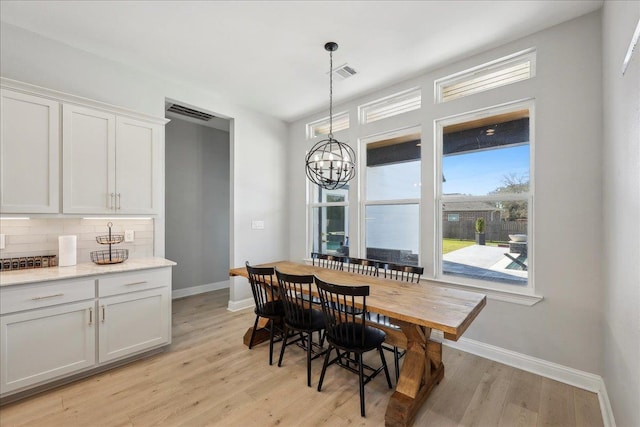 dining space featuring an inviting chandelier, light wood-type flooring, visible vents, and baseboards