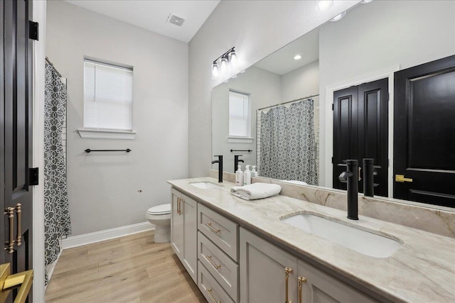 full bathroom featuring toilet, visible vents, a sink, and wood finished floors