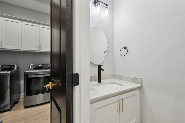 interior space with cabinet space, light wood-style floors, a sink, and independent washer and dryer