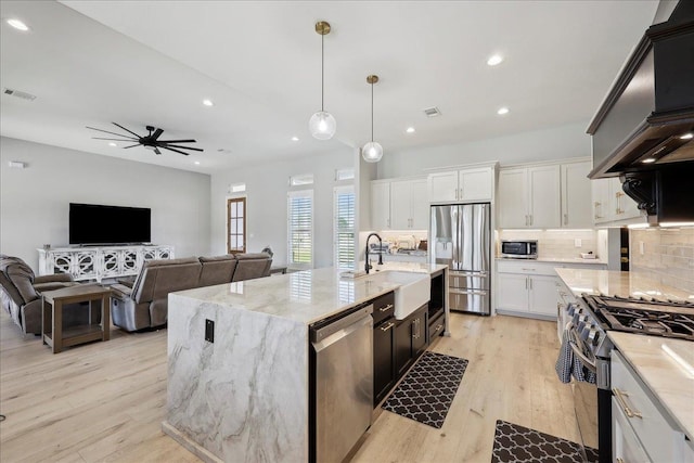 kitchen featuring light wood finished floors, tasteful backsplash, visible vents, appliances with stainless steel finishes, and a sink