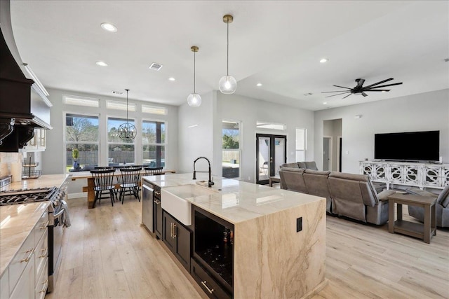 kitchen featuring light wood finished floors, visible vents, appliances with stainless steel finishes, light stone countertops, and a sink