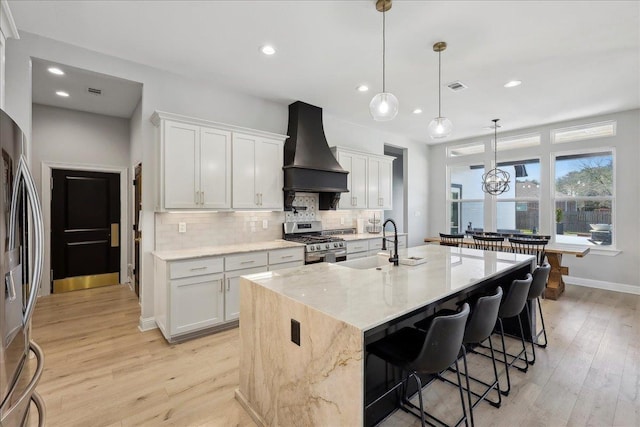 kitchen with stainless steel appliances, visible vents, light wood-style floors, custom exhaust hood, and tasteful backsplash