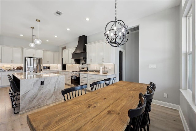 dining room featuring light wood-style flooring, recessed lighting, visible vents, and baseboards