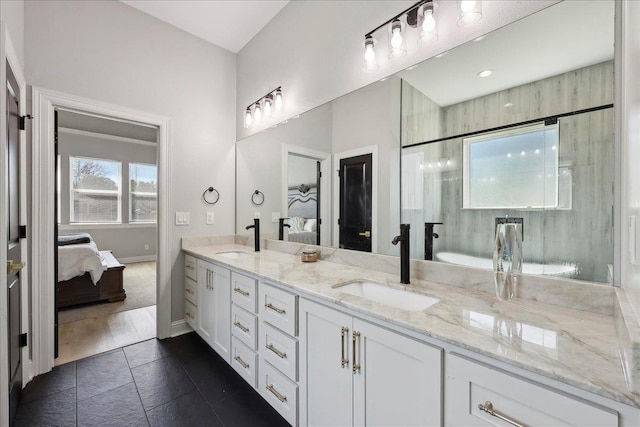 bathroom with baseboards, double vanity, a sink, and connected bathroom