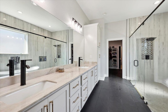 bathroom with double vanity, a spacious closet, a sink, and a shower stall