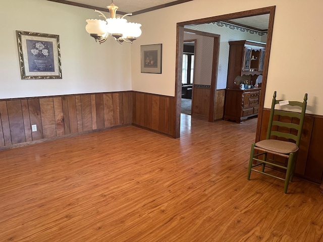 spare room with wood-type flooring, crown molding, and an inviting chandelier