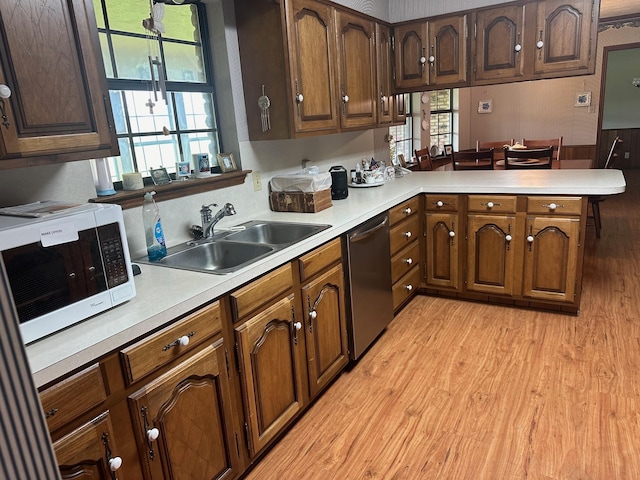 kitchen featuring dishwasher, kitchen peninsula, sink, and light hardwood / wood-style flooring