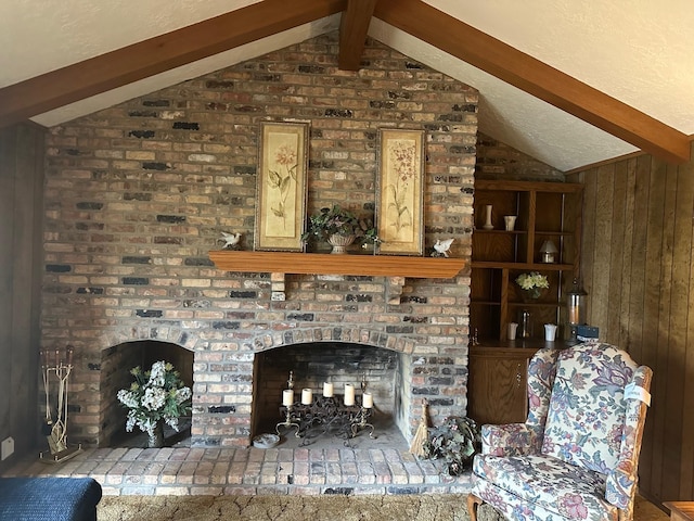 living room with wood walls, lofted ceiling with beams, and a brick fireplace