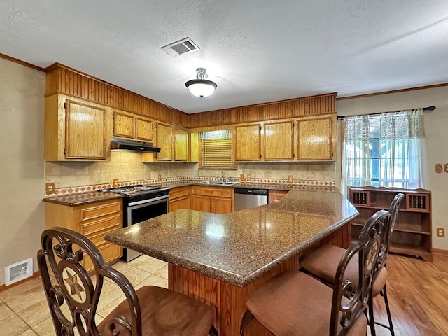 kitchen with sink, a textured ceiling, decorative backsplash, a breakfast bar, and appliances with stainless steel finishes