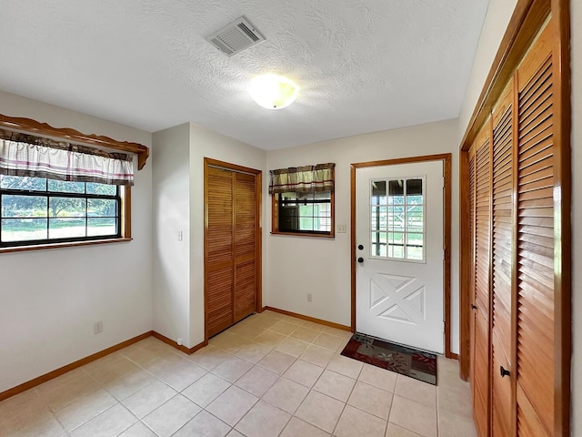 doorway to outside with light tile patterned flooring and a textured ceiling