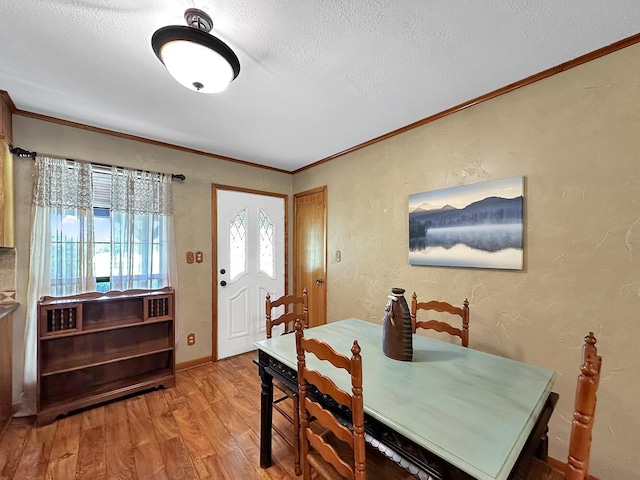 dining space featuring wood-type flooring, a textured ceiling, and ornamental molding