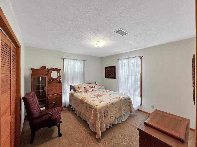 bedroom featuring a textured ceiling, multiple windows, light carpet, and a closet