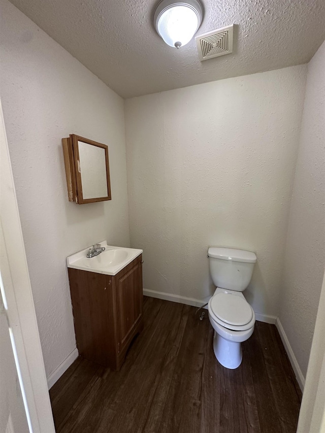 2910 Dowling St, Orange, TX 77630 - half bath with wood finished floors, vanity, toilet, a textured ceiling, and baseboards