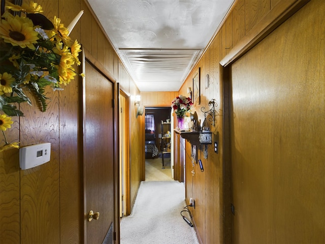 corridor featuring light colored carpet and wooden walls