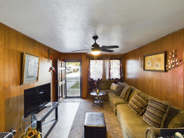 living room featuring light carpet, wooden walls, ceiling fan, and a textured ceiling