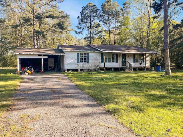 view of front of property with aphalt driveway, a carport, covered porch, and a front yard