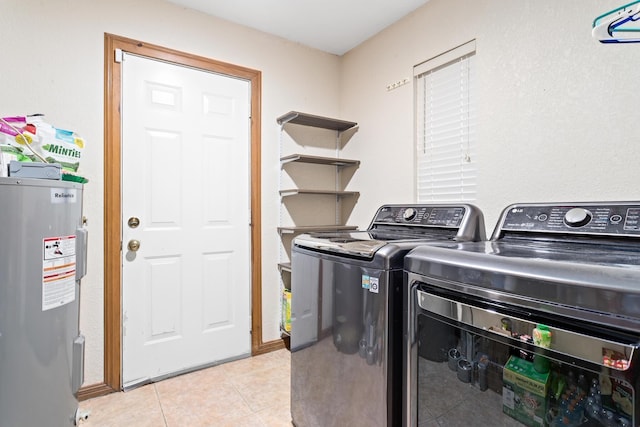 washroom featuring washing machine and clothes dryer, water heater, and light tile patterned floors