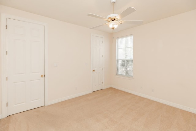 unfurnished room featuring a ceiling fan, light carpet, and baseboards