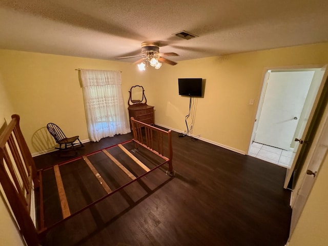 bedroom featuring a textured ceiling, baseboards, visible vents, a ceiling fan, and wood finished floors