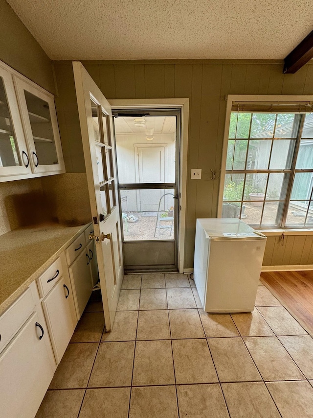 doorway featuring a textured ceiling, wooden walls, and light tile patterned floors