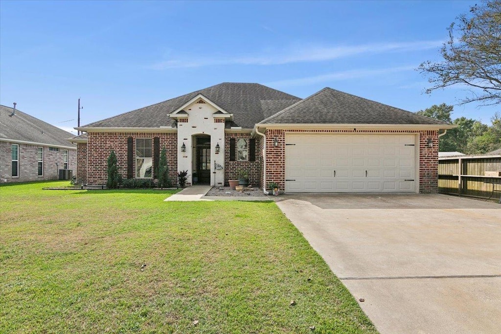 view of front of property with a front yard, a garage, and central air condition unit