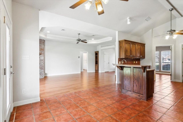 kitchen featuring a tray ceiling, a kitchen bar, a peninsula, and tile patterned flooring