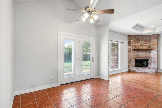 unfurnished living room with tile patterned floors, a fireplace, a raised ceiling, and baseboards