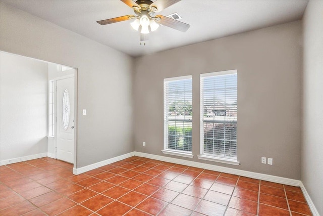 tiled empty room featuring visible vents, baseboards, and ceiling fan