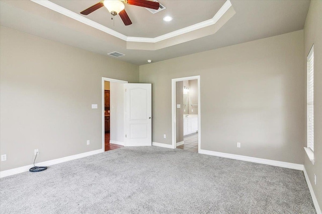 carpeted spare room with visible vents, crown molding, a raised ceiling, and baseboards