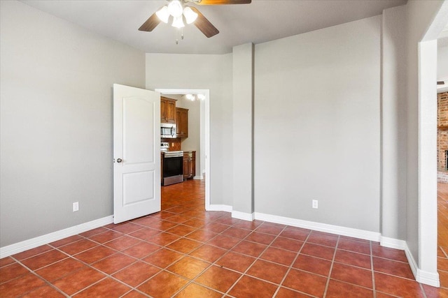 unfurnished room featuring baseboards, a ceiling fan, and dark tile patterned flooring