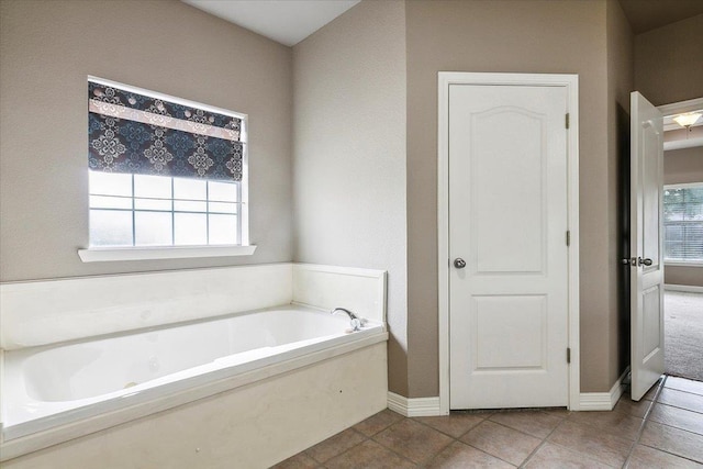 bathroom featuring tile patterned floors, baseboards, and a bath