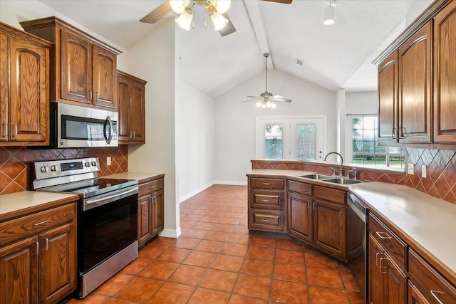 kitchen with dark tile patterned flooring, vaulted ceiling with beams, a sink, stainless steel appliances, and backsplash