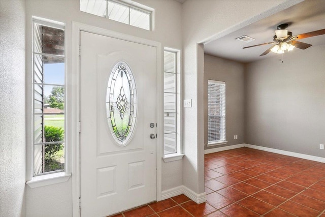 entrance foyer with a ceiling fan, dark tile patterned flooring, baseboards, and visible vents