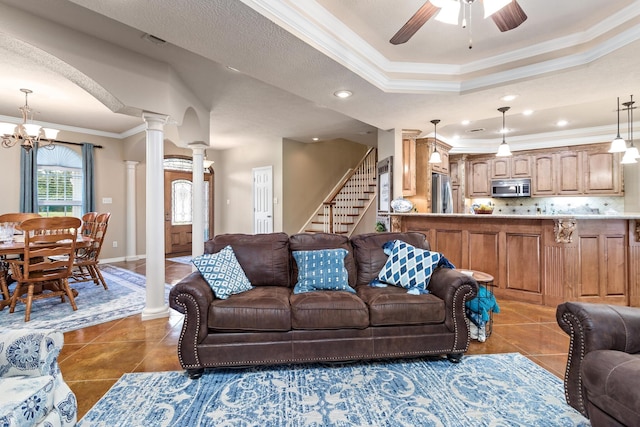 tiled living room featuring ceiling fan with notable chandelier, recessed lighting, decorative columns, a tray ceiling, and ornamental molding
