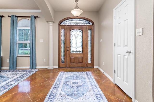 entrance foyer with crown molding, decorative columns, baseboards, dark tile patterned flooring, and arched walkways