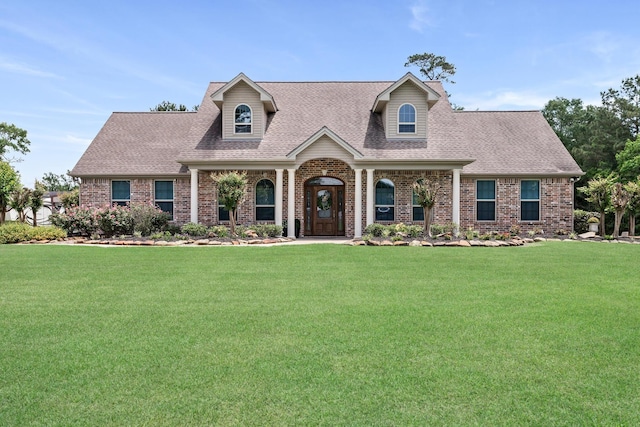 cape cod home featuring brick siding, a shingled roof, and a front yard