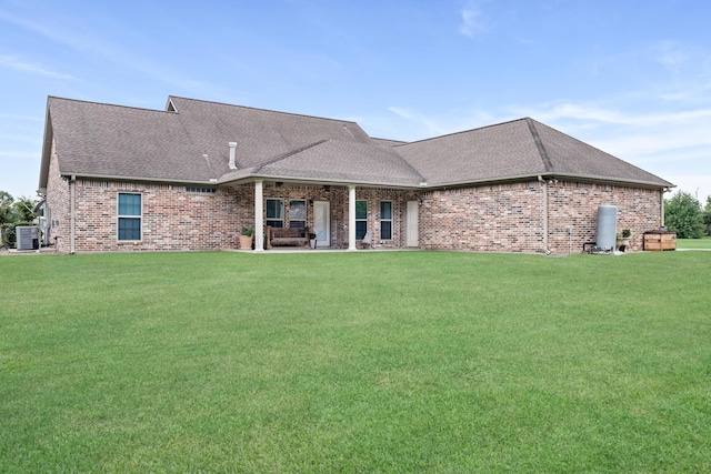 rear view of house featuring brick siding, roof with shingles, central air condition unit, and a yard