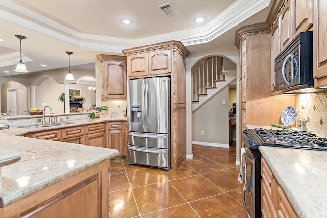 kitchen with a sink, a raised ceiling, decorative columns, and stainless steel appliances