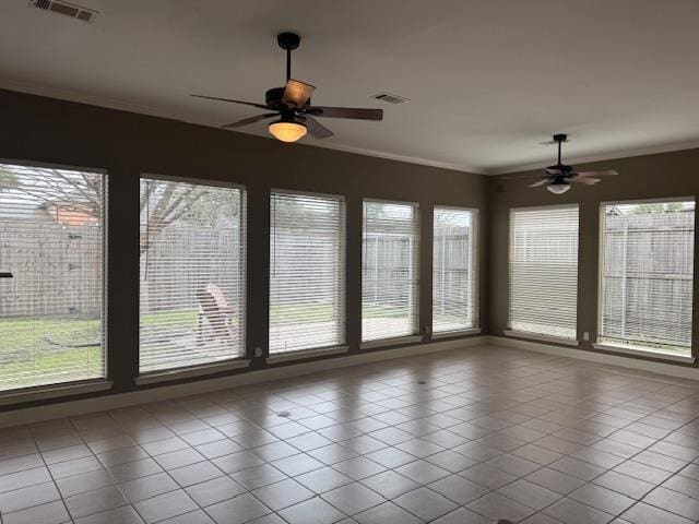 unfurnished sunroom with plenty of natural light, visible vents, and a ceiling fan