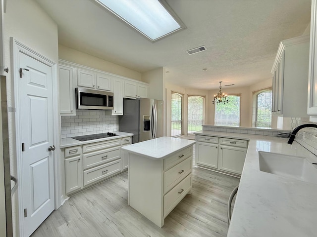 kitchen with a chandelier, light wood-type flooring, a sink, and stainless steel appliances