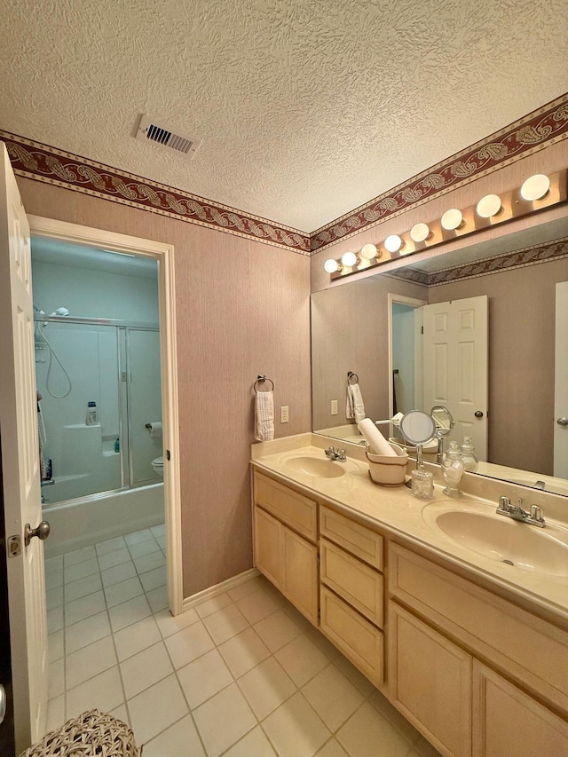 bathroom featuring a sink, visible vents, double vanity, and a textured ceiling