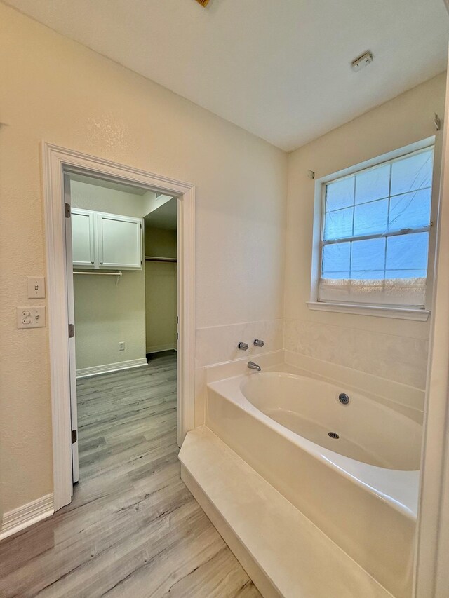 full bathroom with wood finished floors, baseboards, and a garden tub