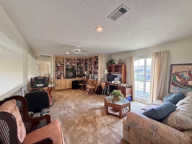 living room with light carpet, ceiling fan, visible vents, and a textured ceiling