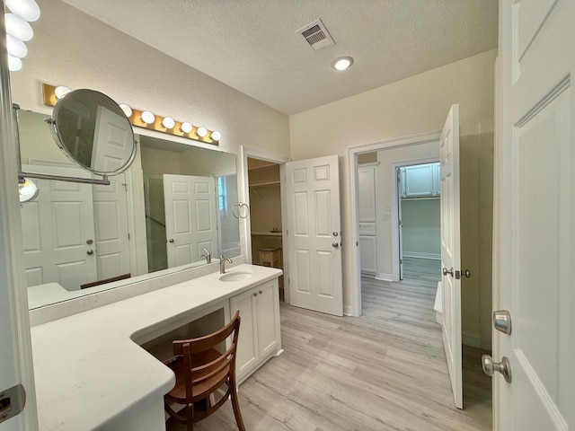 bathroom featuring visible vents, a textured wall, a textured ceiling, vanity, and wood finished floors