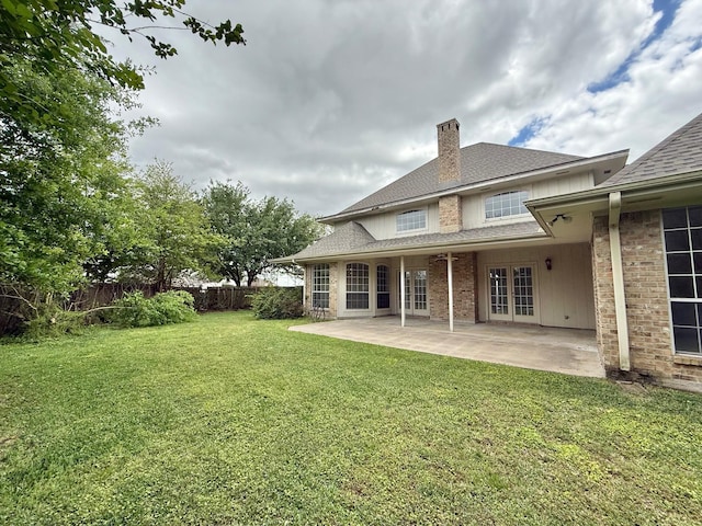 back of property featuring a chimney, french doors, a patio area, a yard, and fence