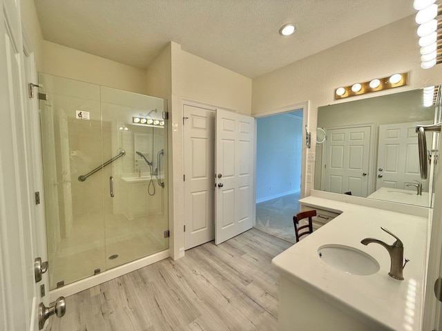 full bathroom featuring a shower stall, vanity, a textured ceiling, and wood finished floors