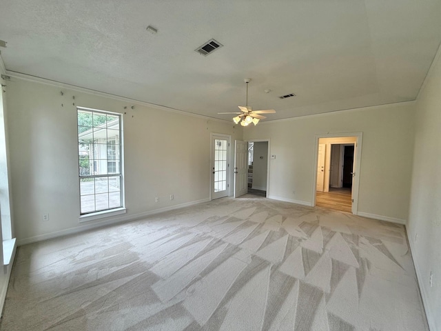 unfurnished room with crown molding, a ceiling fan, visible vents, light carpet, and baseboards