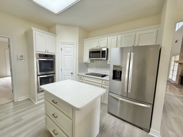kitchen featuring light wood-type flooring, a center island, white cabinetry, decorative backsplash, and stainless steel appliances
