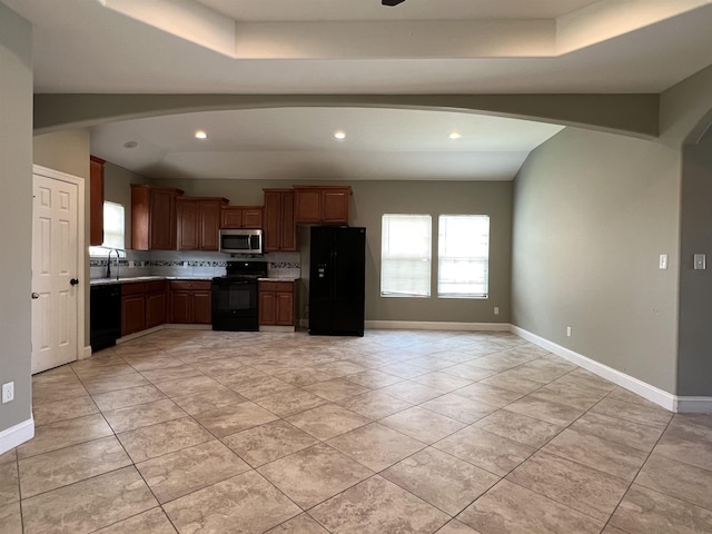 kitchen featuring light tile patterned flooring, vaulted ceiling, sink, and black appliances